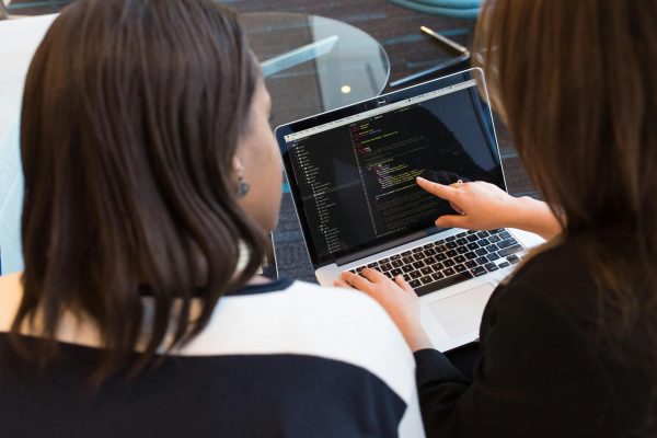 pexels-photo-1181263-1181263 Two women working together on software programming indoors, focusing on code.