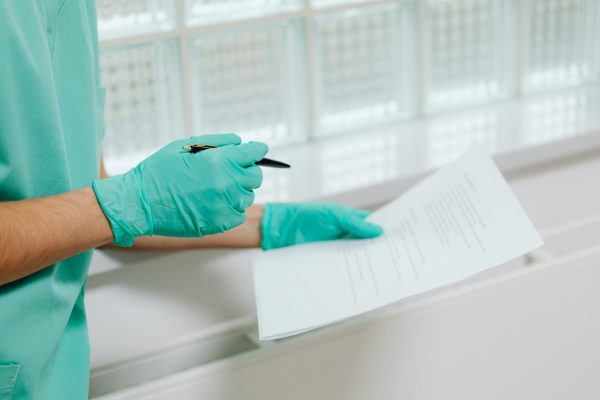 pexels-photo-6627822-6627822 Close-up of a healthcare professional in gloves holding and reading a medical document indoors.