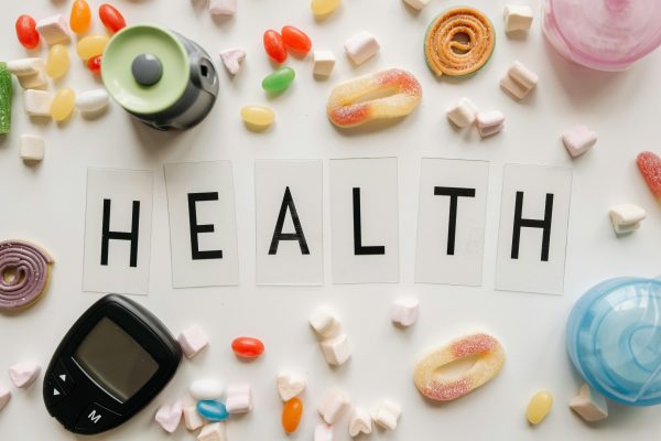 pexels-photo-7653345-7653345 Creative flat lay with sweets around a 'HEALTH' text and monitoring device, symbolizing diabetes awareness.